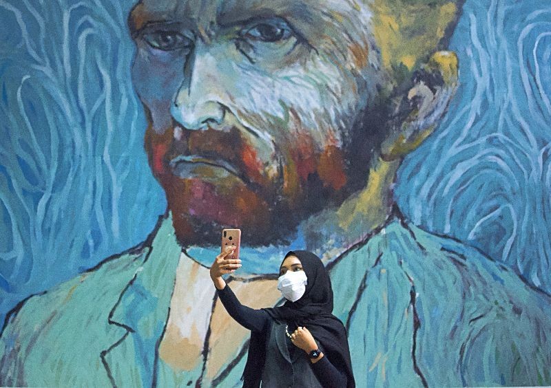 A visitor wearing a protective face mask takes a selfie near an art-wall painted by Indonesian artist Hanafi at Kertas Gallery during an exhibition in Depok, near Jakarta, Indonesia . REUTERS/Ajeng Dinar Ulfiana